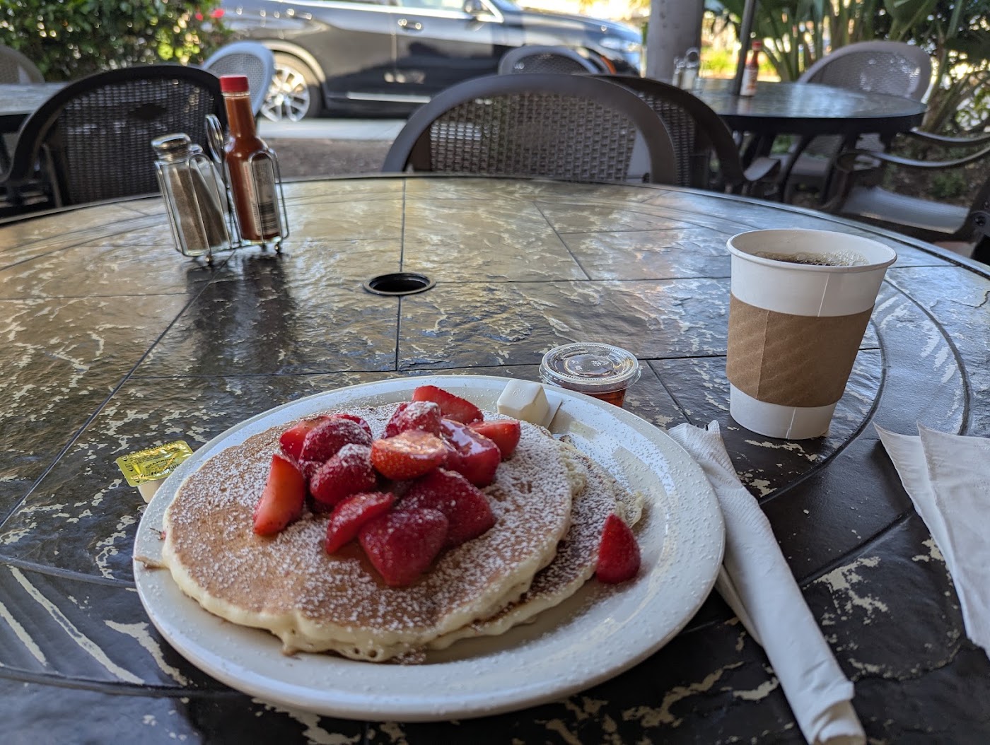 Pancakes with strawberries and coffee on a Cafe Elysa patio table